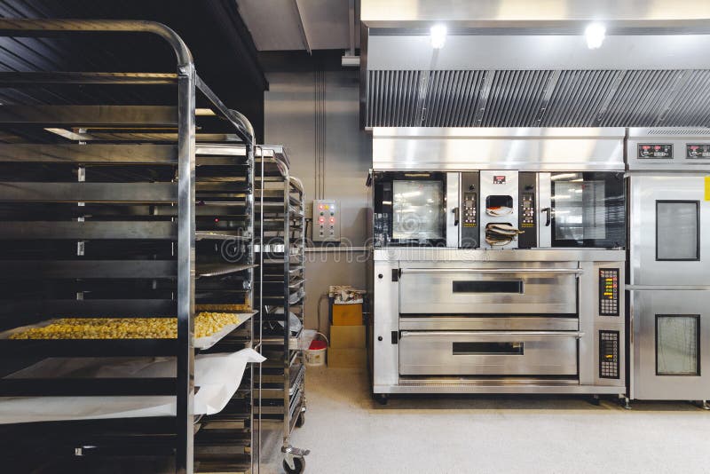 Modern pastry kitchen decorated in black, white and steel with baking machine, oven, conveyor, production line, mixer. Modern pastry kitchen decorated in black stock photos