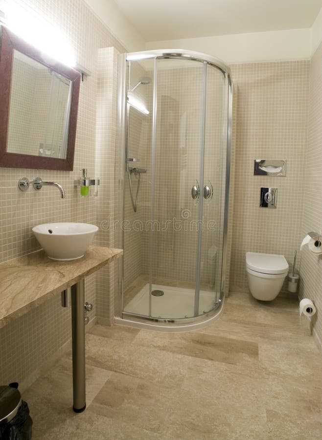 Modern shower and toilet. A picture of the interiors of a modern bathroom, with shower stall, toilet, sink and mirror. Decorated in a beige colour scheme royalty free stock photo