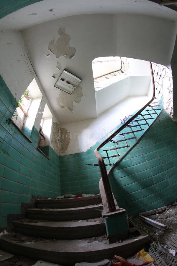 Old broken staircase with turquoise tiles, stone stairs and metal railing with wooden handrail. Several floors house.  stock images