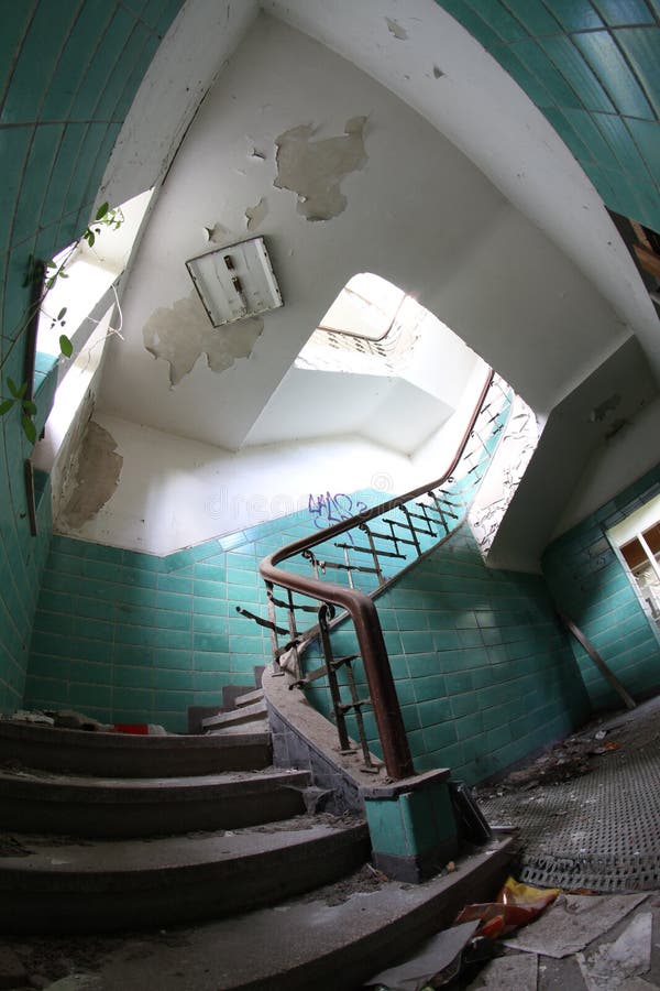 Old broken staircase with turquoise tiles, stone stairs and metal railing with wooden handrail. Several floors house.  stock photography