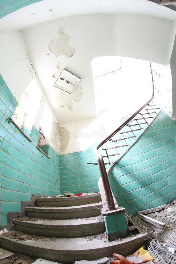 Old broken staircase with turquoise tiles, stone stairs and metal railing with wooden handrail. Several floors house.  stock images