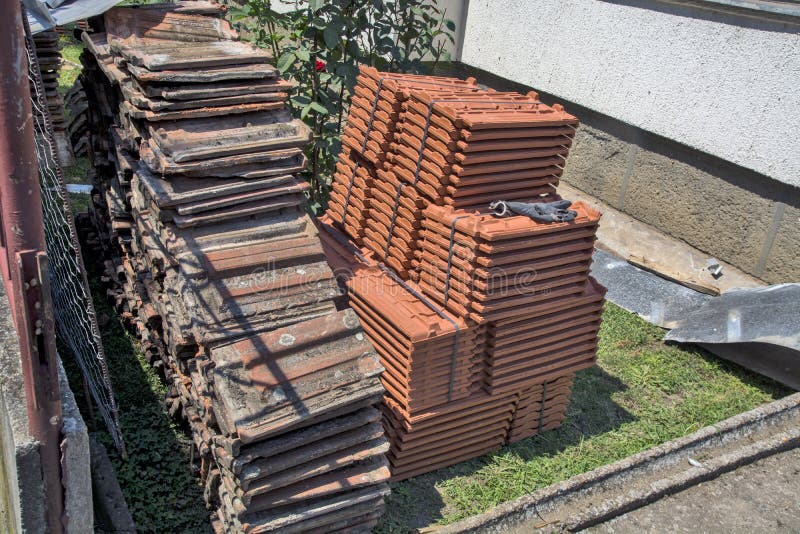 Old and new tiles on the ground. Home yard and stored old and new tiles. The new tile is waiting for the preparation of the supporting wooden construction, which stock photo