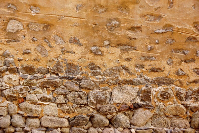 Old Stone Wall Made From Granite Rocks And Ripped Plaster royalty free stock image