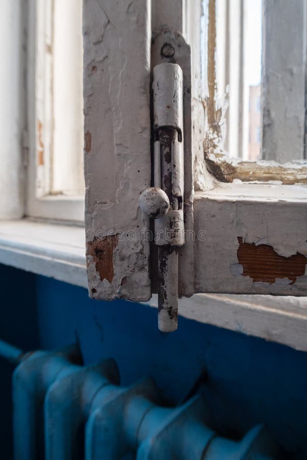 Old window with a latch. Fragment of an open old window with an old latch and peeling paint stock image