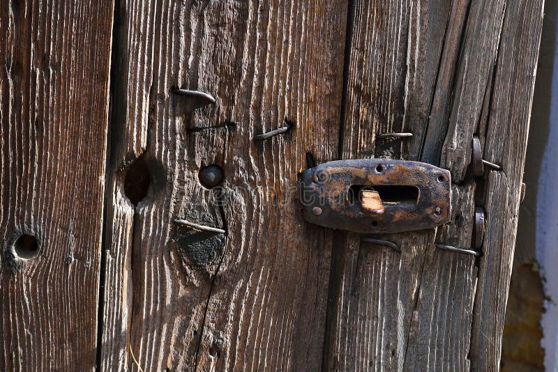 Old wooden door, closeup of door handle, closing mechanism. Rusted iron components and old creased wood surface stock photo