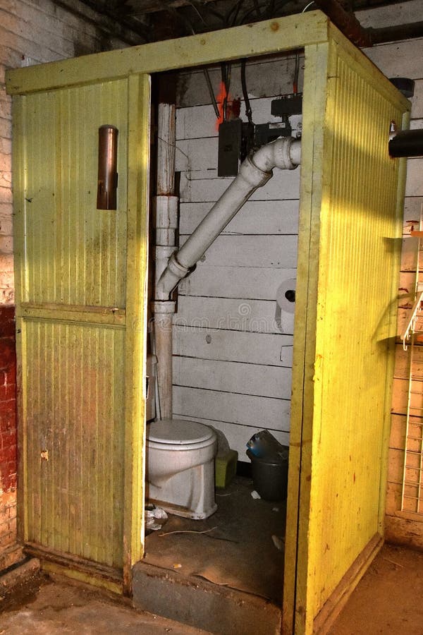 Old yellow outhouse in a basement warehouse stock photo