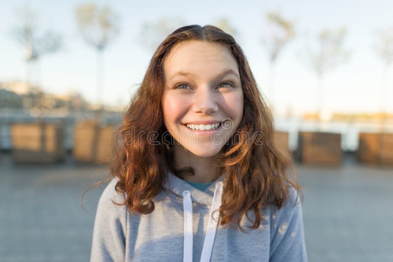 Outdoor portrait of beautiful smiling teenager girl 14, 15 years old. Golden hour stock photography