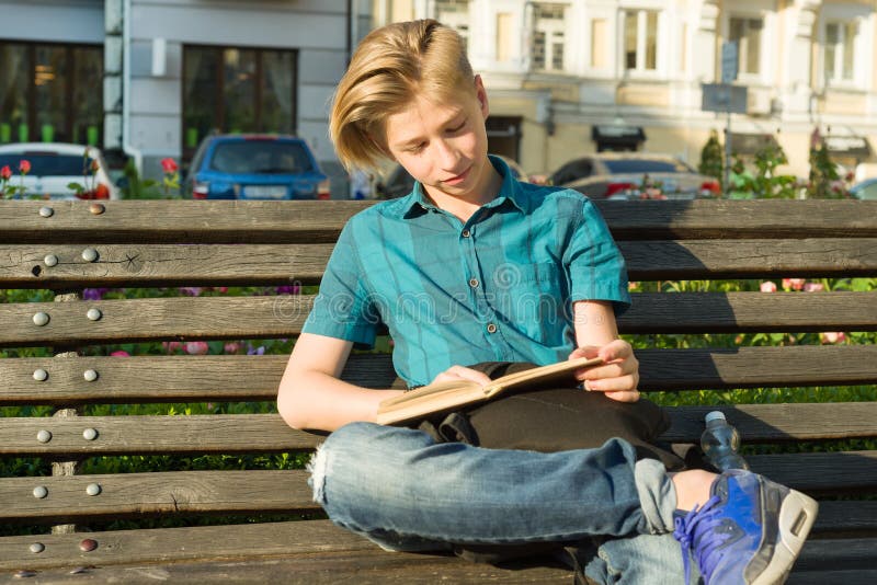 Outdoor portrait of a teenage boy and girl 14, 15 years old, sitting on bench in city park with book. Outdoor portrait of a teenage boy and girl 14, 15 years royalty free stock images