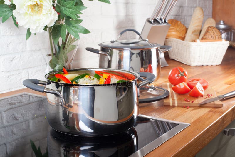 Pan on the stove with vegetables in kitchen interior. Home royalty free stock images