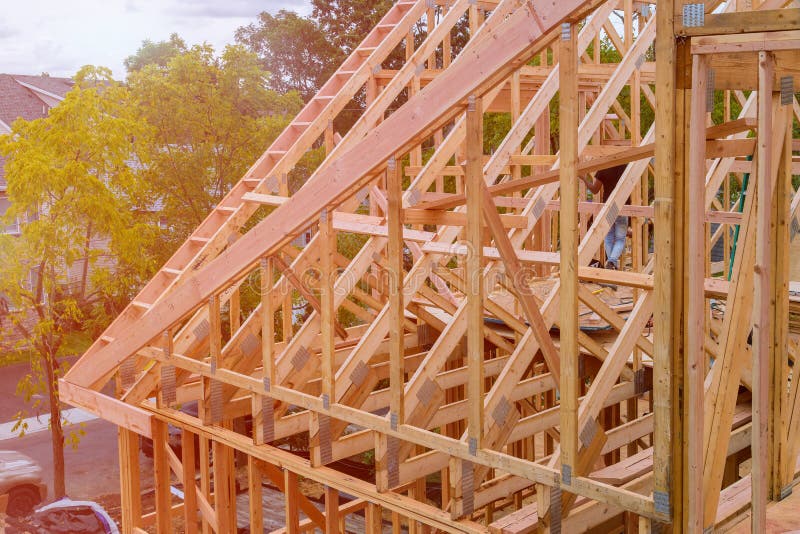 Panorama of condominium building with under construction wooden house with timber framing, truss, joist, beam close-up. Panorama of modern condominium building royalty free stock photo