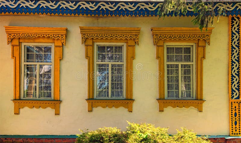 Сarved wooden platbands on three yellow windows of traditional Ukrainian village house. stock photography