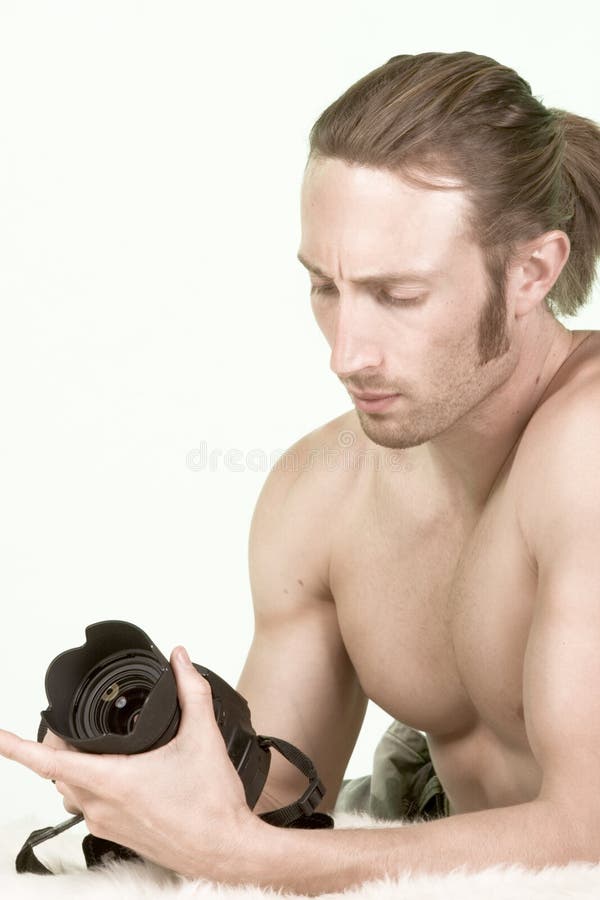 Photographer man with Muscular Build checks camera. Young Caucasian shirtless male with great biceps checks his photo camera settings royalty free stock photo