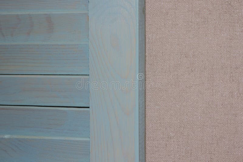 Blue jalousie door in combination with beige wallpaper. A piece of bleached blue jalousie door in combination with plain beige wallpaper stock image