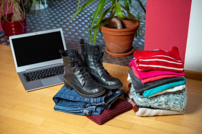 Pile of second hand clothing and shoes with computer on floor royalty free stock photography