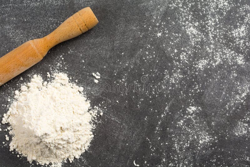 Pile of wheat flour and a rolling pin on a messy granite kitchen counter.  royalty free stock photography
