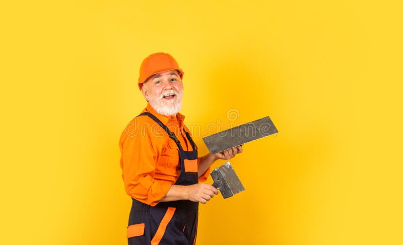 Plaster trowel spatula on yellow drywall plasterboard. Plasterer in working uniform plastering. man with spatula. Process of applying layer of putty royalty free stock images