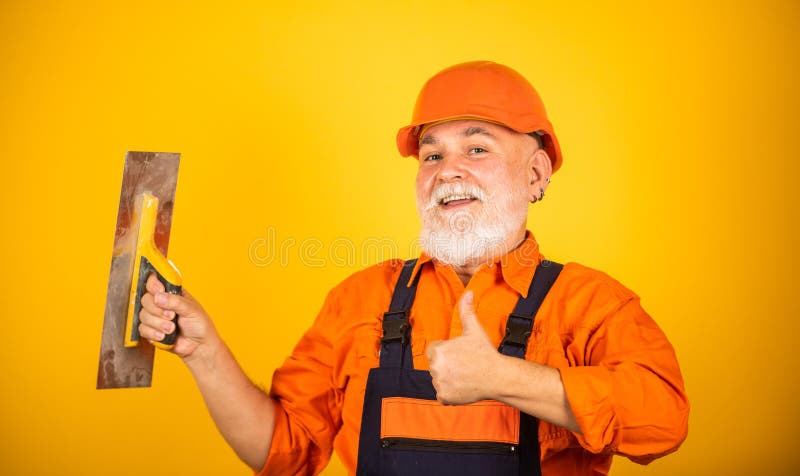Plastering tools for plaster. plaster trowel spatula on yellow drywall plasterboard. Plasterer in working uniform. Plastering wall indoor. man with spatula royalty free stock image