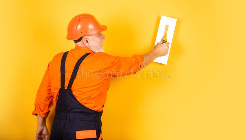 Plastering tools for plaster. plaster trowel spatula on yellow drywall plasterboard. Plasterer in working uniform. Plastering wall indoor. man with spatula royalty free stock photography