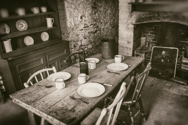 Poor peasants interior from 19th century, dining room with set wooden table and fireplace, sepia style photography stock image