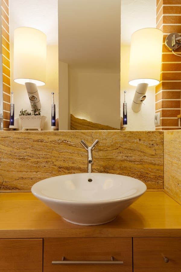 Porcelain washbasin in loft bathroom. Photo of washbasin in loft bathroom arranged in warm colors stock images