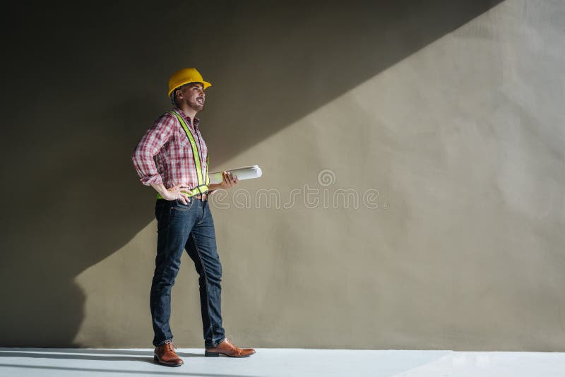 Portrait of an architect builder studying layout plan of the rooms, serious civil engineer working with documents on construction royalty free stock image