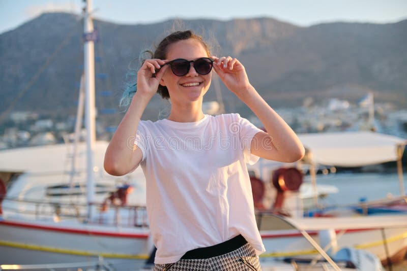 Portrait of teenage girl 15 years old, happy smiling teenager. Summer sunset sea harbor with yachts background. Vacation, adolescence, travel concept royalty free stock images