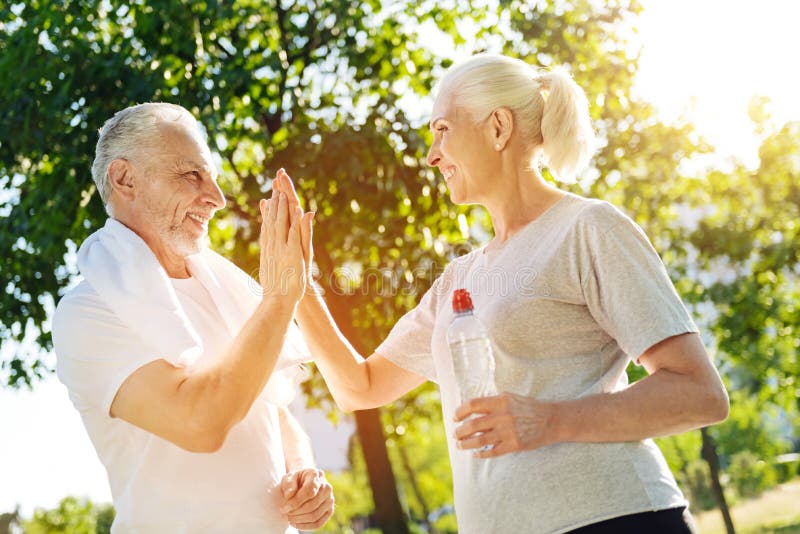 Positive aged couple resting in the park after jogging royalty free stock photo