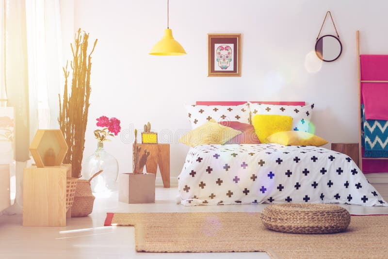 Pouf in folk bedroom interior. Pouf on brown carpet in bedroom interior with yellow lamp, round mirror and cactus. Folk bedroom concept royalty free stock photos