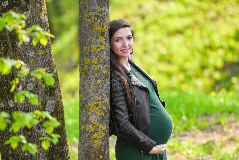 Pregnant schoolgirl. Attractive pregnant woman in dress schoolgirl posing on the street. Long-haired pregnant woman walking down stock photo