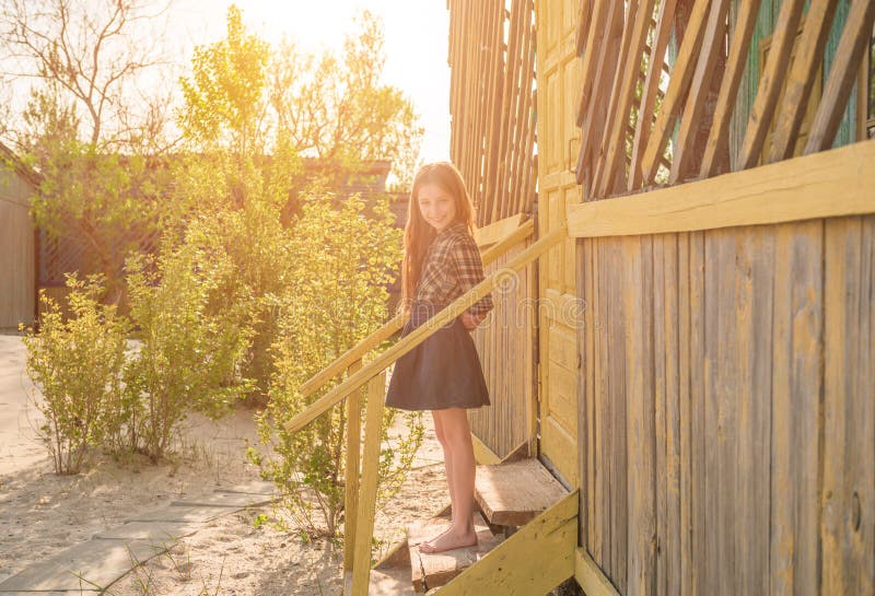 Pretty little girl on stairs of wooden house. Pretty little barefoot girl on stairs of wooden house at a seaside in sunlight stock images