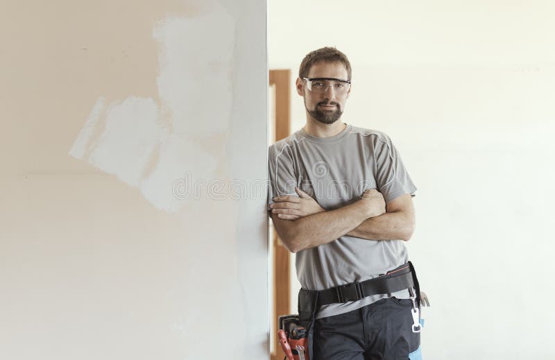 Professional repairman posing and apartment under renovation royalty free stock images