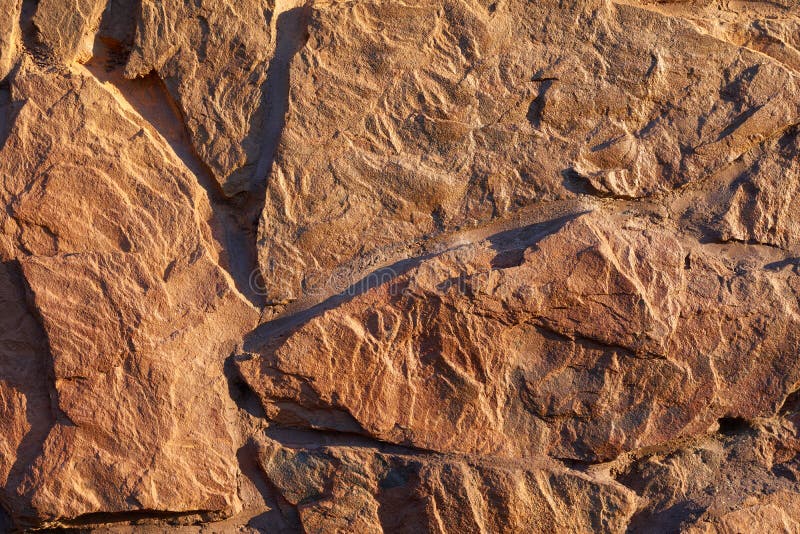 Artificial stone finishing. Red stone textured finishing on the foundation of the house royalty free stock photo