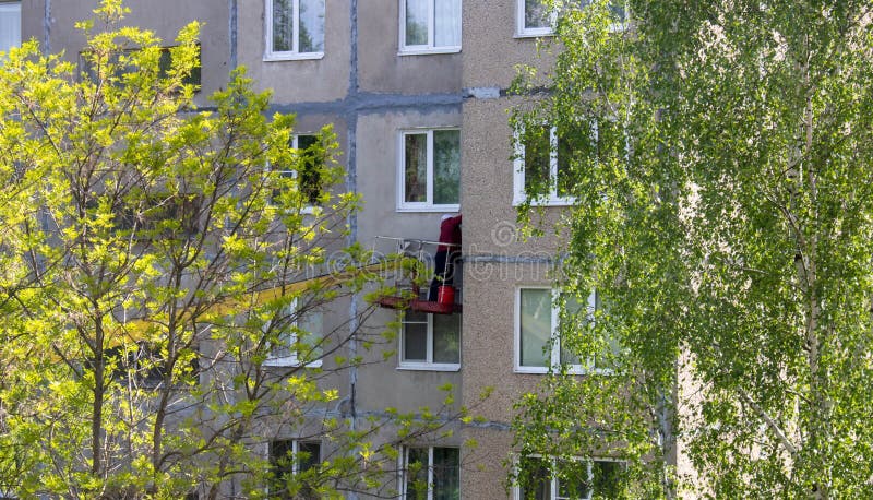 Repair work on the facade of the building. in the stage of maintenance.A woman plasters the facade of a multi-storey building.  stock photography