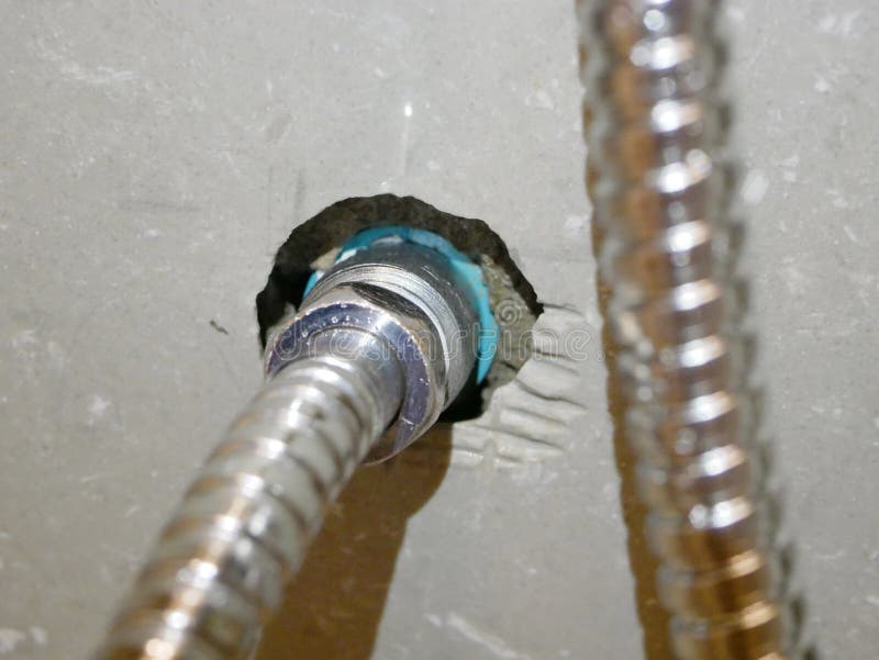 Rinsing spray hose connected to the water pipe, through a metalic joint with female - male thread. Close up of the rinsing spray hose connected to the water pipe stock image