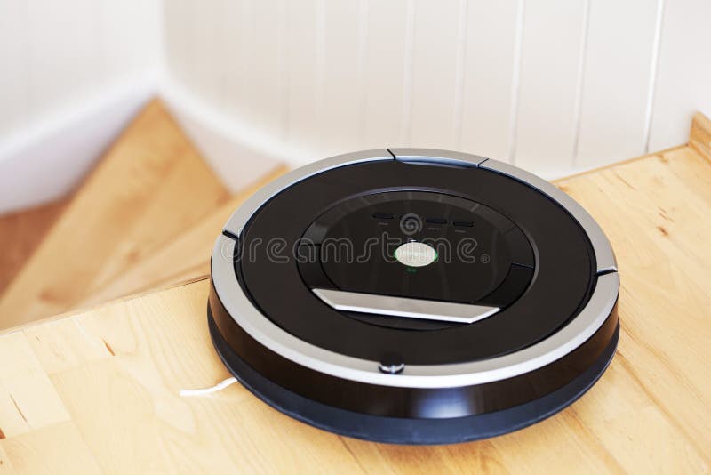 Robotic vacuum cleaner on laminate wood floor smart cleaning technology stairs.  royalty free stock photos