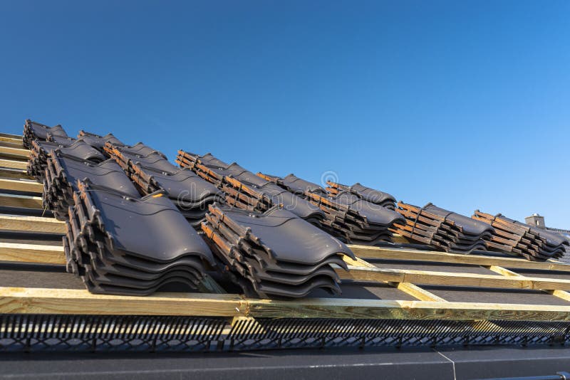 Roof ceramic tile arranged in packets on the roof on roof battens. Preparation for laying roof tiles. Roof ceramic tile arranged in packets on the roof on roof stock image