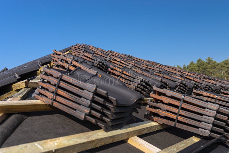 Roof ceramic tile arranged in packets on the roof on roof battens. Preparation for laying roof tiles. Roof ceramic tile arranged in packets on the roof on roof stock photo