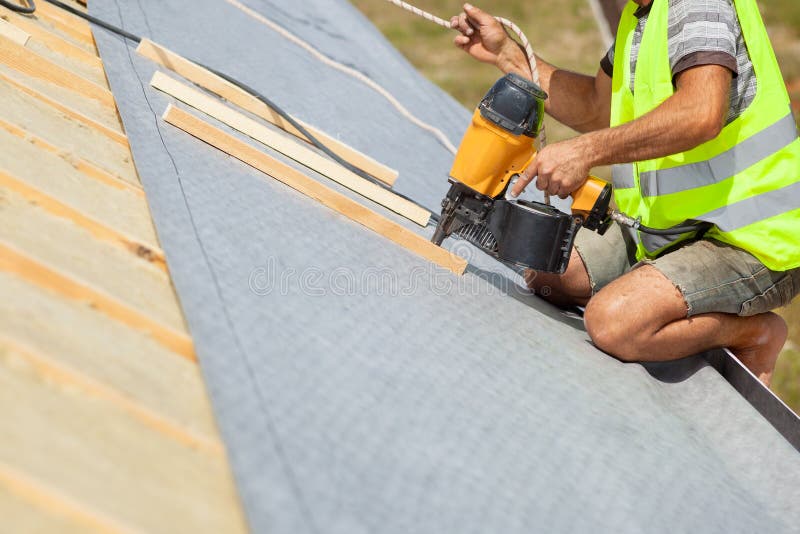 Roofer builder worker use automatic nailgun to attach roofing membrane. royalty free stock image