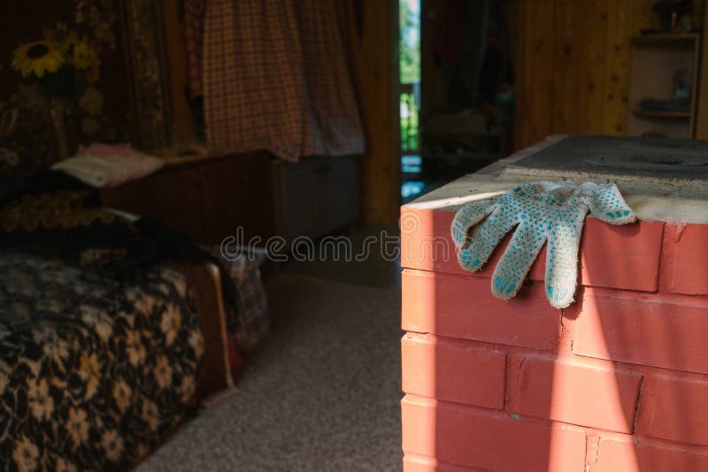Russian old interior with an oven. Russian old interior village with an oven and a sofa. Dirty glove on red brick oven stock image