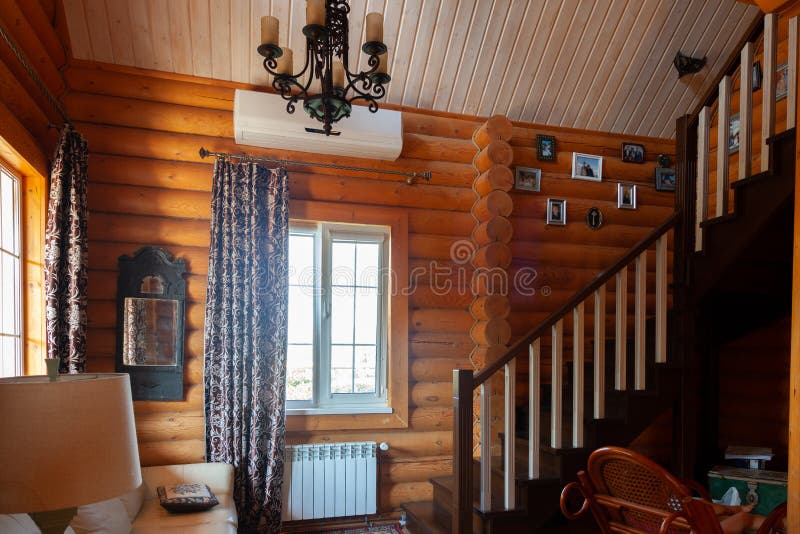 Rustic house, log cabin inside, wooden staircase to the second floor, light from the Windows royalty free stock image