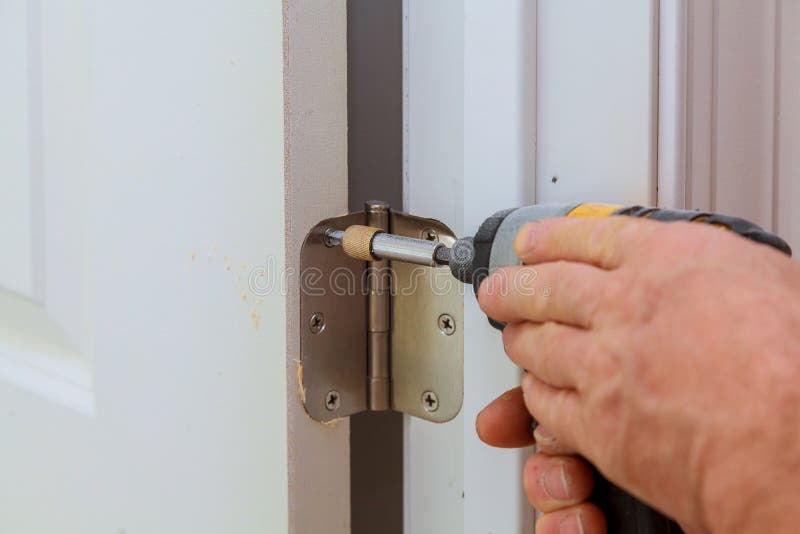 Screwing hinge installation on a process of wood door. Screwing metal chrome hinges installation on a process of wood door royalty free stock photography