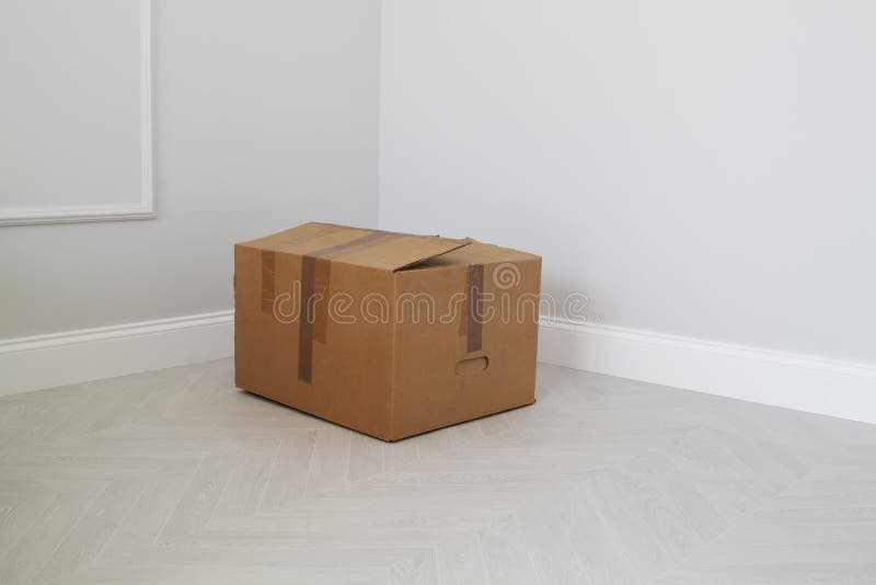 Shabby cardboard box in the corner in an empty new room.  stock image