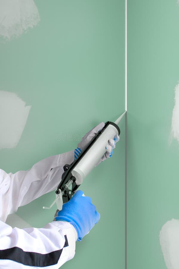 Silicone sealant gun fills the joint between plasterboars. Construction worker with silicone sealant gun fills the joint between plaster boars in dry wall in wet royalty free stock images