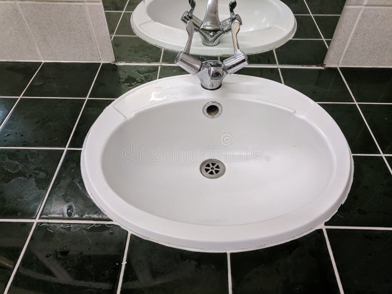 Sink with black tiling and white grouting. Black tiles white grouting and mirror with sink amd taps stock image