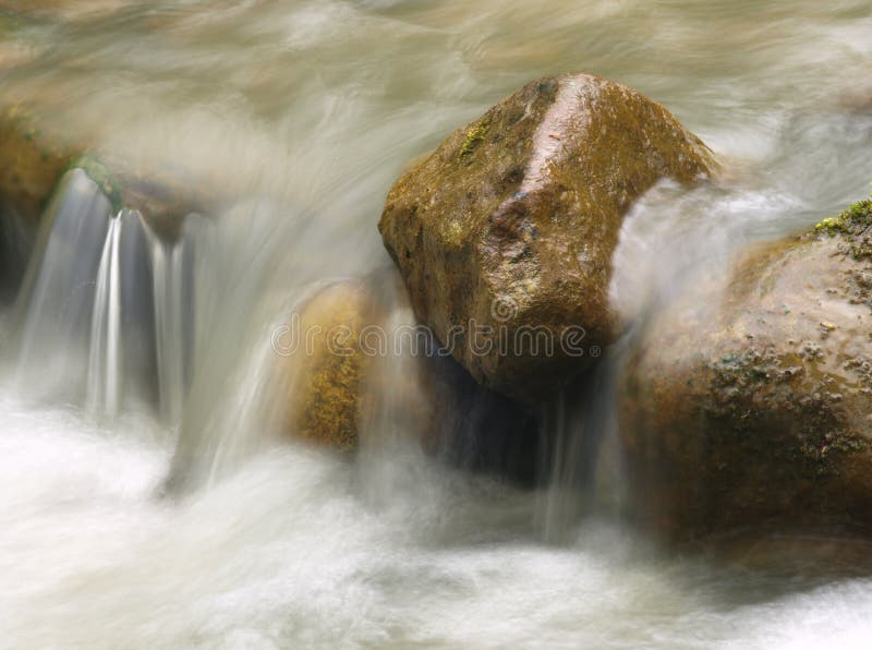 Small waterfall in the mountain river. Beautiful natural background of stones and with flowing, blurring water and foaming. stock photography
