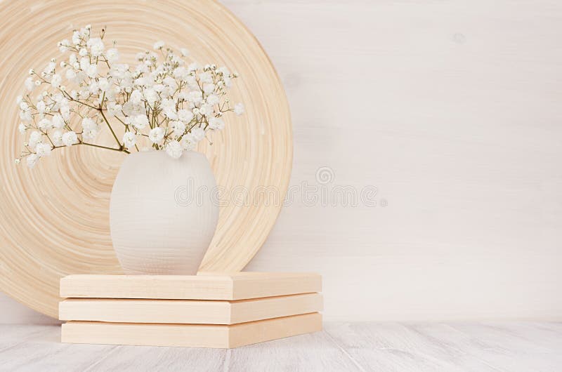 Soft home decor of beige bamboo dish and white small flowers in ceramic vase on white wood background. Interior. Soft home decor of beige bamboo dish and white royalty free stock image