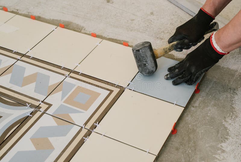 Specialist for laying tiles aligns the tiles with a carpenter`s royalty free stock photos