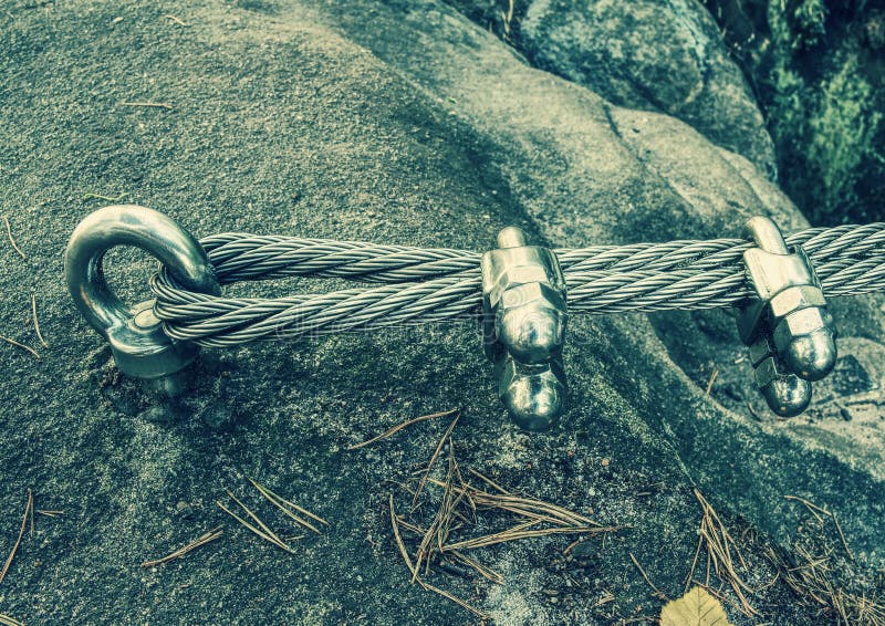 Stainless cable fixed to the rock for the safety. Mountain iron anchor for free climbing. Stainless cable fixed to the rock for the safety of the walking route stock images