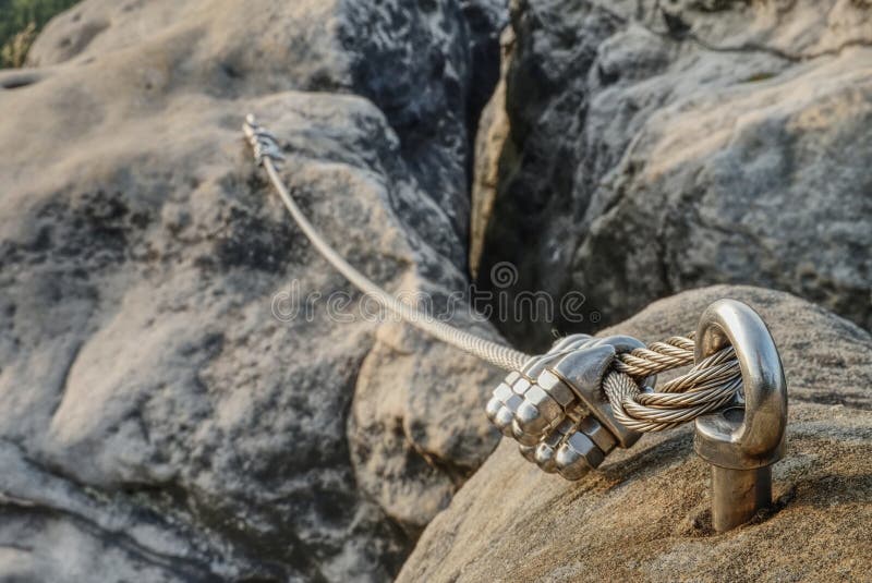 Stainless cable fixed to the rock for the safety. Mountain iron anchor for free climbing. Stainless cable fixed to the rock for the safety of the walking route stock photo
