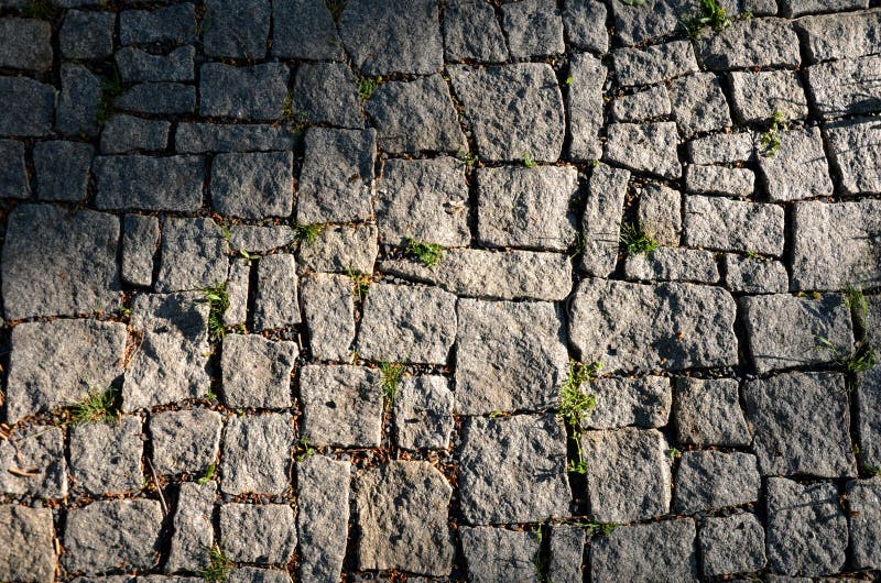 Granite paving of irregular sections of chipped stone around a park with green lawn gray color of the pedestrian path. Stone, wall, texture, pattern, bark, old royalty free stock photo